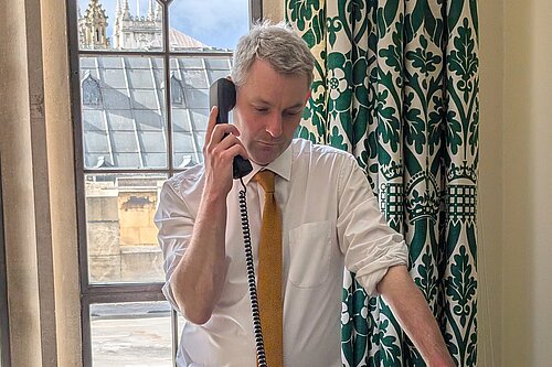 Will Forster Will Forster speaking on the phone in his Westminster office, he is wearing a white shirt with the sleeves rolled up and a yellow tie.